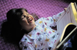 Young girl laughing while reading book