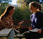 Two women sitting on bench talking
