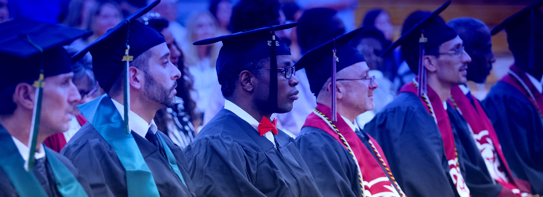 Graduating inmates sitting in caps and gowns during a Higher Education in Prison commencement ceremony.