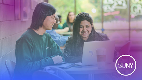 Two SUNY students look at a laptop at a table outside with SUNY logo at the bottom.