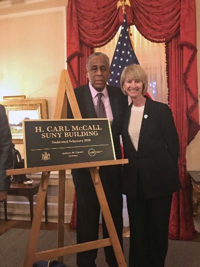 SUNY Board Chairman emeritus H. Carl McCall stands with Chancellor Kristina Johnson behind the new sign for the H. Carl McCall SUNY Building.