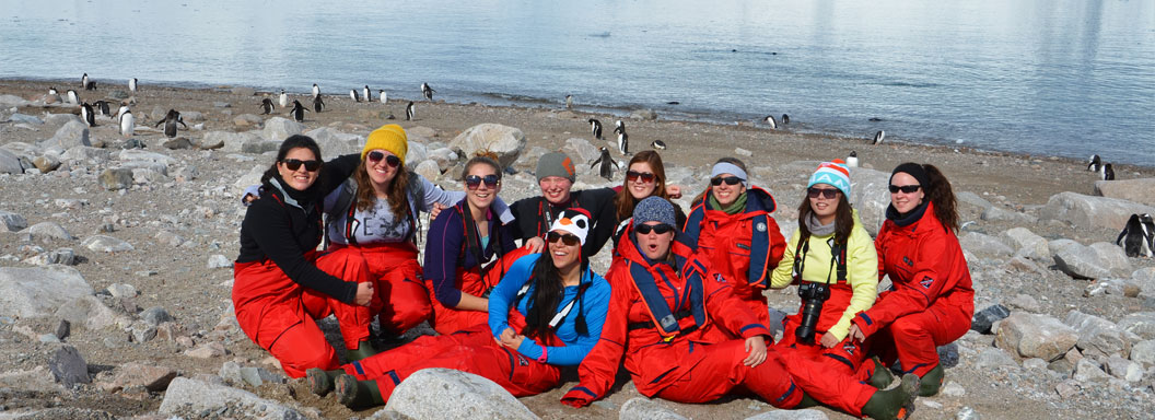 Students from the College at Brockport sit on the ground in Antarctica.