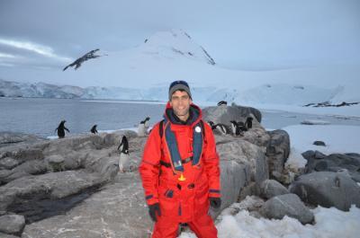 A male student from the College at Brockport stands before a mountain in Antarctica. 