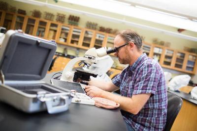 Professor Nicholas Warner looks at moon rock samples through a microscope.