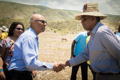 Chairman Carl McCall shakes hands with a local at a Sustainable Village and Learning Community gathering in Haiti. 