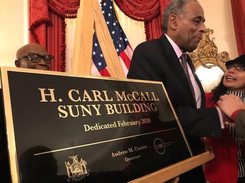 SUNY Board Chairman H Carl McCall stands next to the new sign for the H Carl McCall SUNY Building at the Governor's mansion.