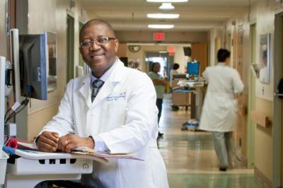 Upstate Medical University doctor stands in front of computer station in hospital hallway.