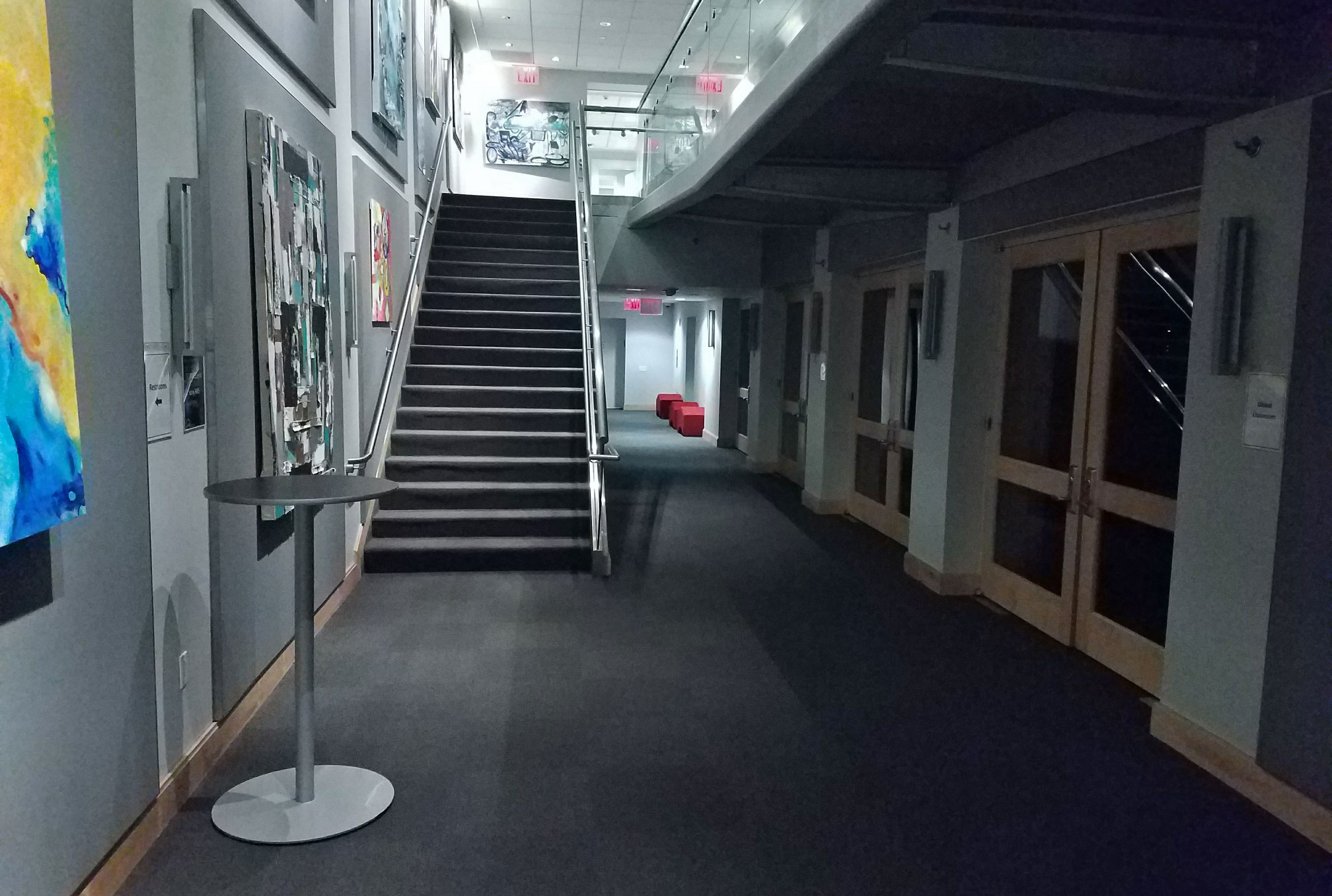 Common area at the bottom of a staircase with the SUNY Global Center global classroom to the right.