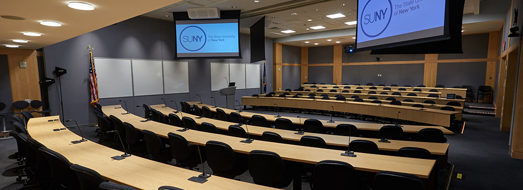  The SUNY Global Center classroom with large screen monitors hanging from the ceiling. 