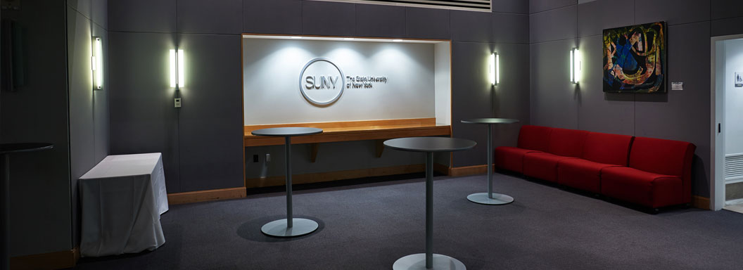 The reception area in front of the SUNY Global Center classroom with a SUNY logo hanging inside a large inset wall.
