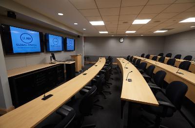 A tiered classroom at the SUNY Global Center with 3 large monitors on the front wall. 