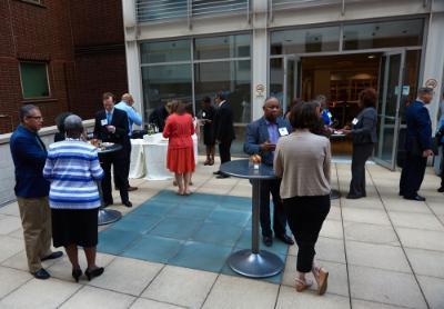  The SUNY Global Center outdoor terrace, connected to the cafe, with people standing around cocktail tables talking. 