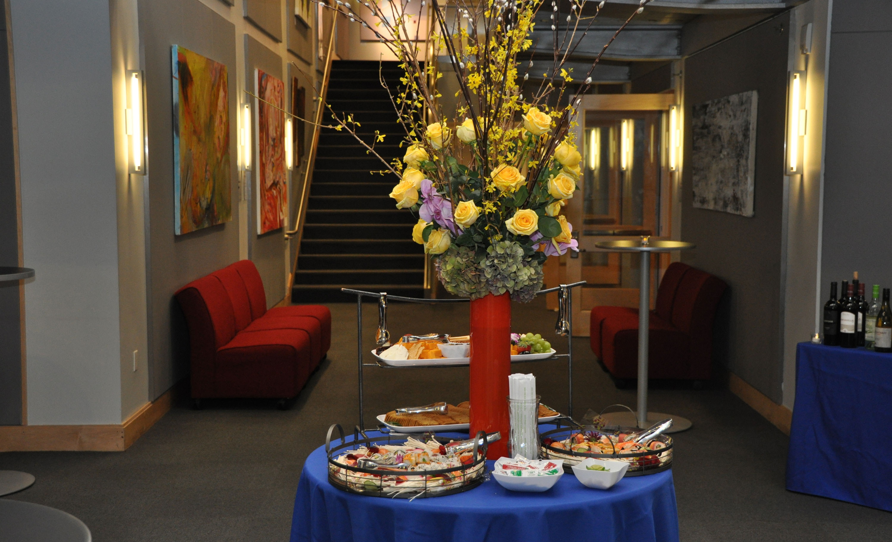 Tall flowers in vase on a high-top table in the SUNY Global Center reception space outside the global classroom.