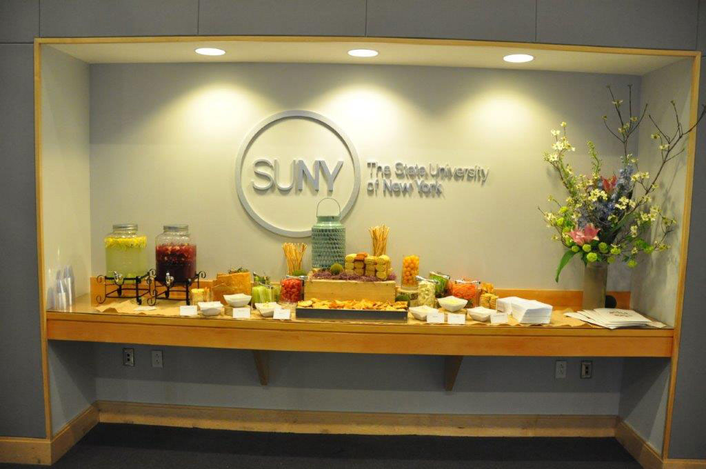 A buffet station along the wall with a large SUNY logo on wall over it.