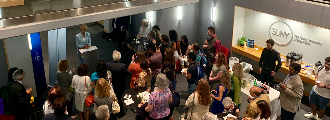 Overhead photo of a large event crowd gathered in the reception area outside the global classroom at the SUNY Global Center.