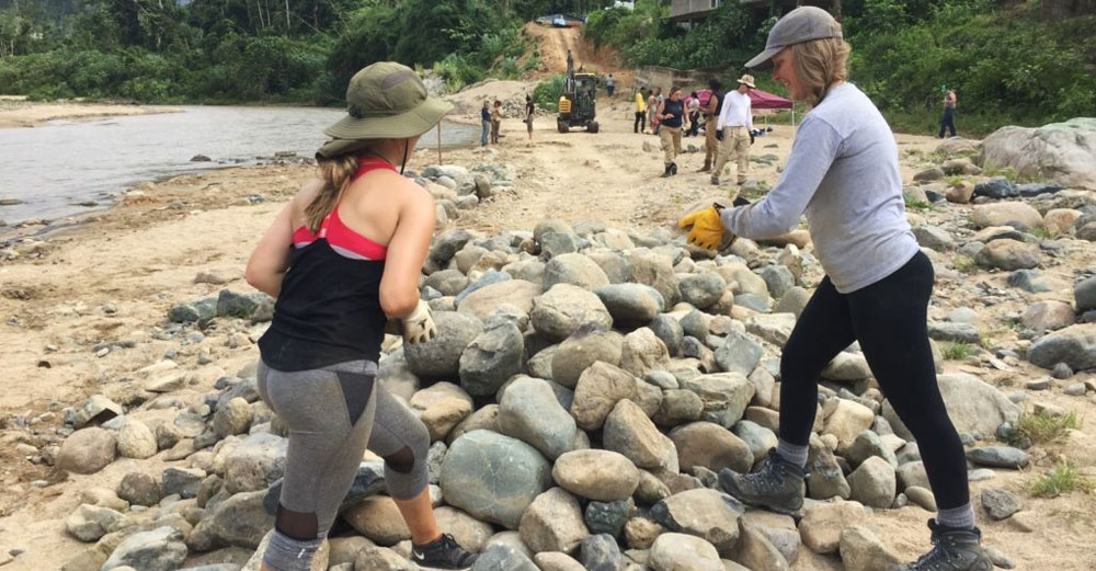 2 females students from SUNY ESF move debris on a beach in Puerto Rico.
