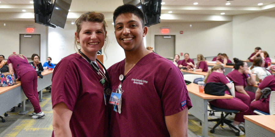 A male and female nursing student pose for a picture in Corning Community College nurse scrubs.