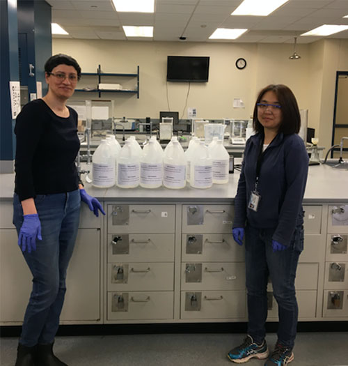 Chemistry students at Stony Brook University stand next to bottles of hand sanitizer they made for COVID19 response.