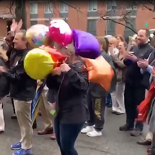 SUNY Brockport staff carry balloons outside a dorm building as they sing happy birthday to a student inside.