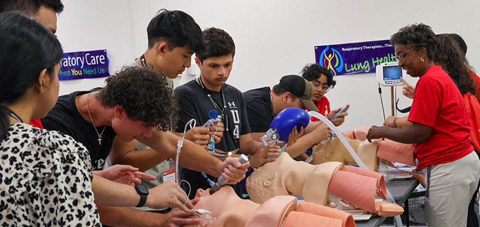 Medical students practice respiratory therapy techniques on dolls.