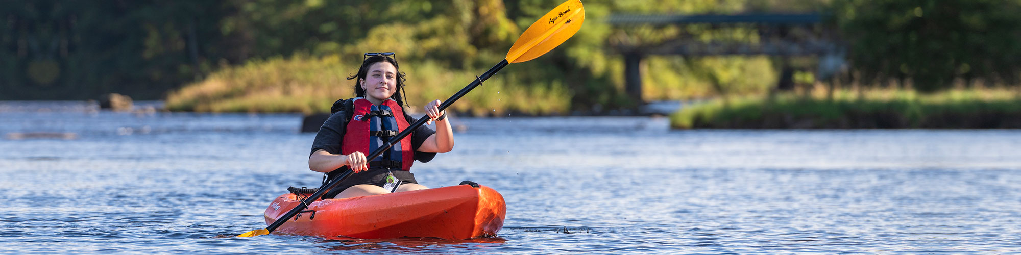 A female college student kayaks in a lake.