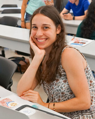 Female student in class at Stony Brook University smiles for a photo.
