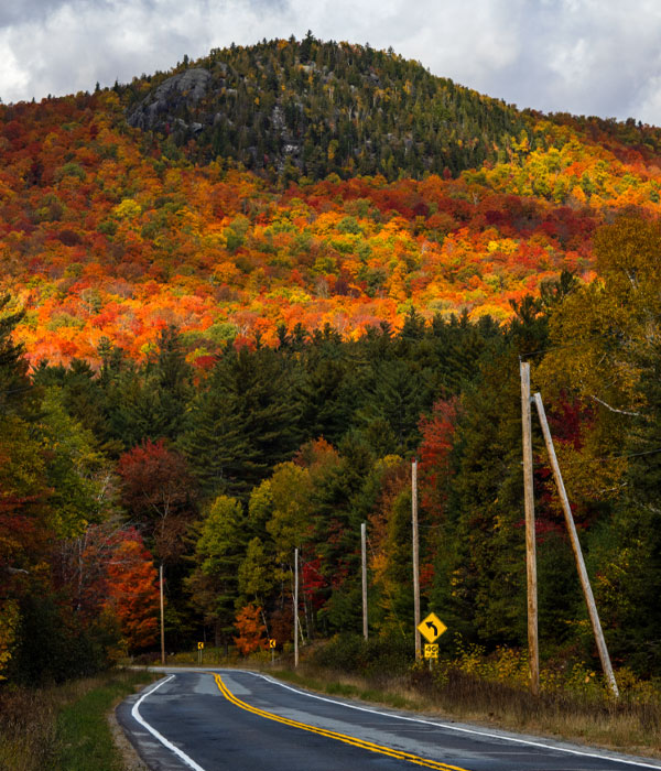 Scenic road in front of the Adirondack Mountains full of fall foliage