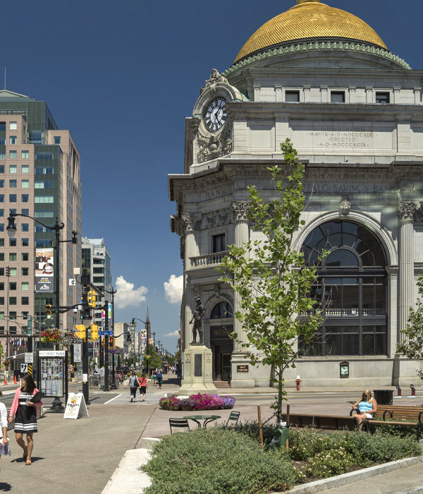 People walking on the street in front of a big gold domes building in Downtown Buffalo NY