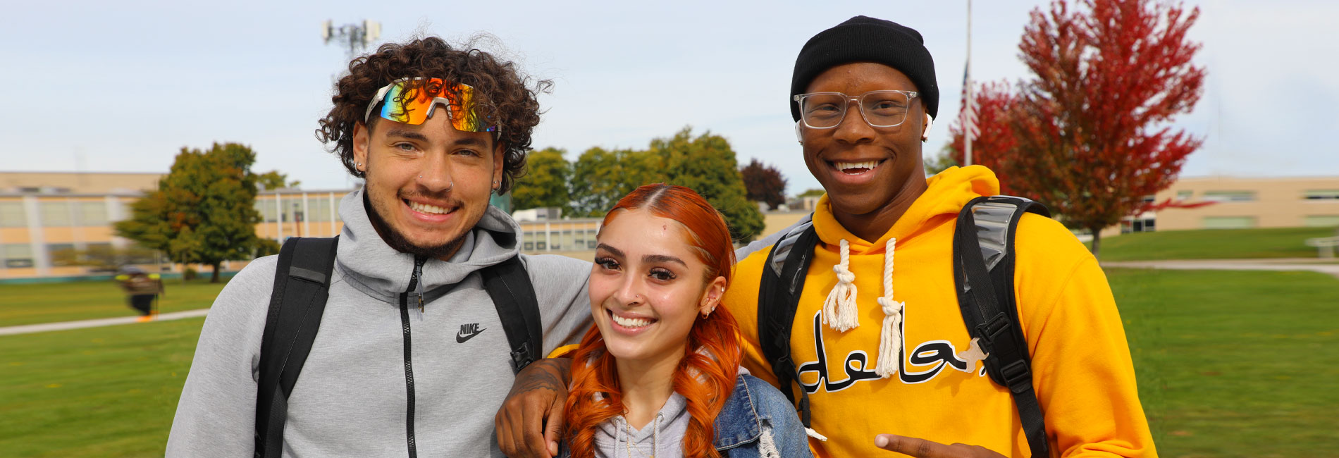 Two male and one female student pose for a picture outside on the campus of Erie Community College.