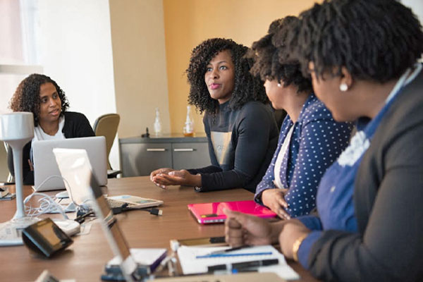 African American female talks to coworkers at an office conference table.
