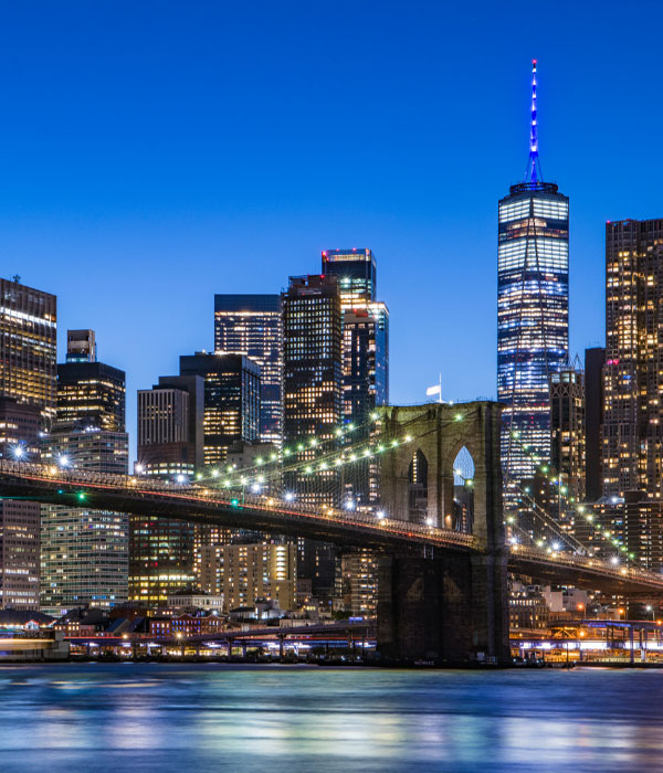 Brooklyn Bridge with NYC skyline and the Freedom Tower behind it lit up at night
