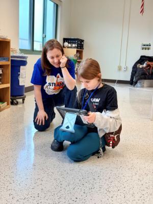 A Student sitting with educator on floor