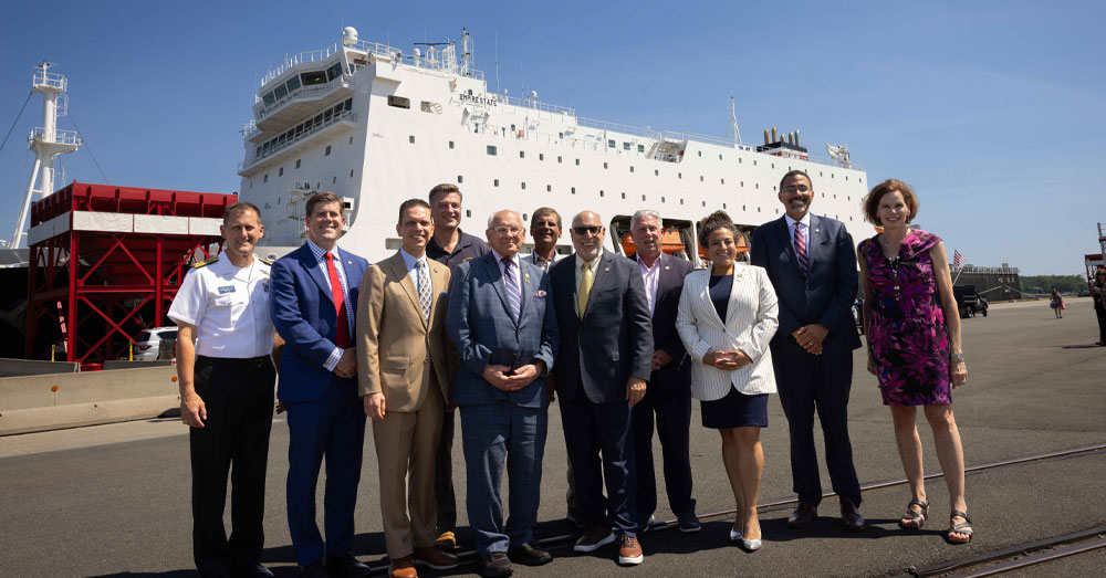SUNY Chancellor John B. King Jr. stands with SUNY Maritime faculty and staff and a group of Albany area legislators at the port of Albany in front of the SUNY Maritime College training ship the Empire State VII.