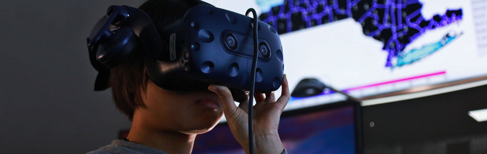 A woman wears VR goggles in a science lab.