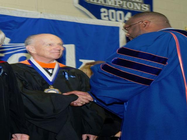 Professor Emeritus Richard Macy being congratulated by Dr. Shaun McKay, President of Suffolk County Community College, Presidential Medal