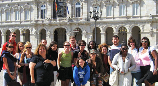 Students pose for a picture while in front of a white building in Italy.