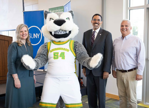 SUNY Chancellor John B. King Jr. stands with Adirondack Community College president Anastasia Urtz and mascot Eddy Rondack during an ACE expansion event.