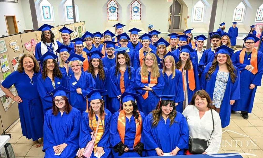Clinton Community College graduates dressed in their blue commencement gowns pose for a group picture.