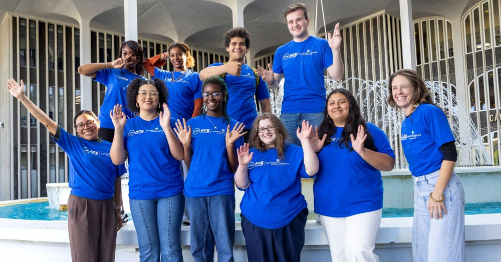 ACE students in blue SUNY ACE tshirts stand in front of the UAlbany Campus Center fountain.