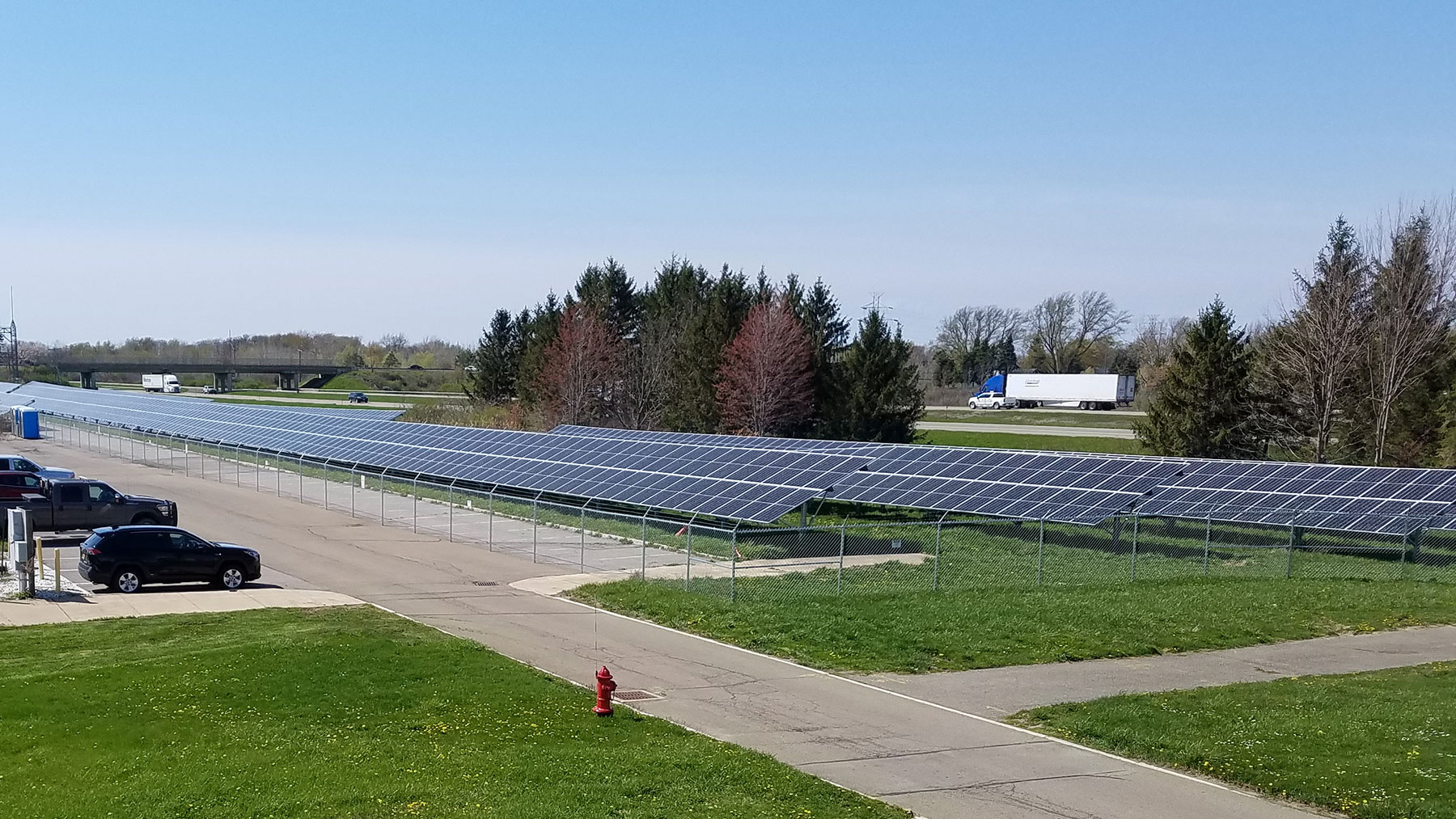Solar panel array on a grass field behind a parking lot at SUNY Fredonia