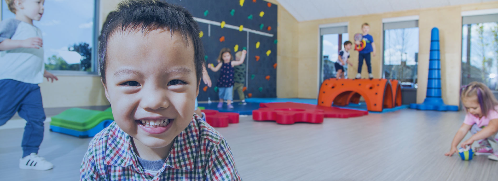 An asian child smiles at camera inside a child care center. 